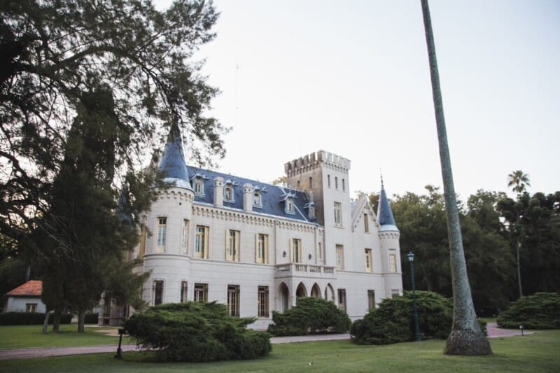 A castle in a green lawn with pine trees