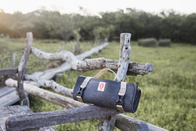 A compact blue yoga mat is folded up and sitting on a wooden bench