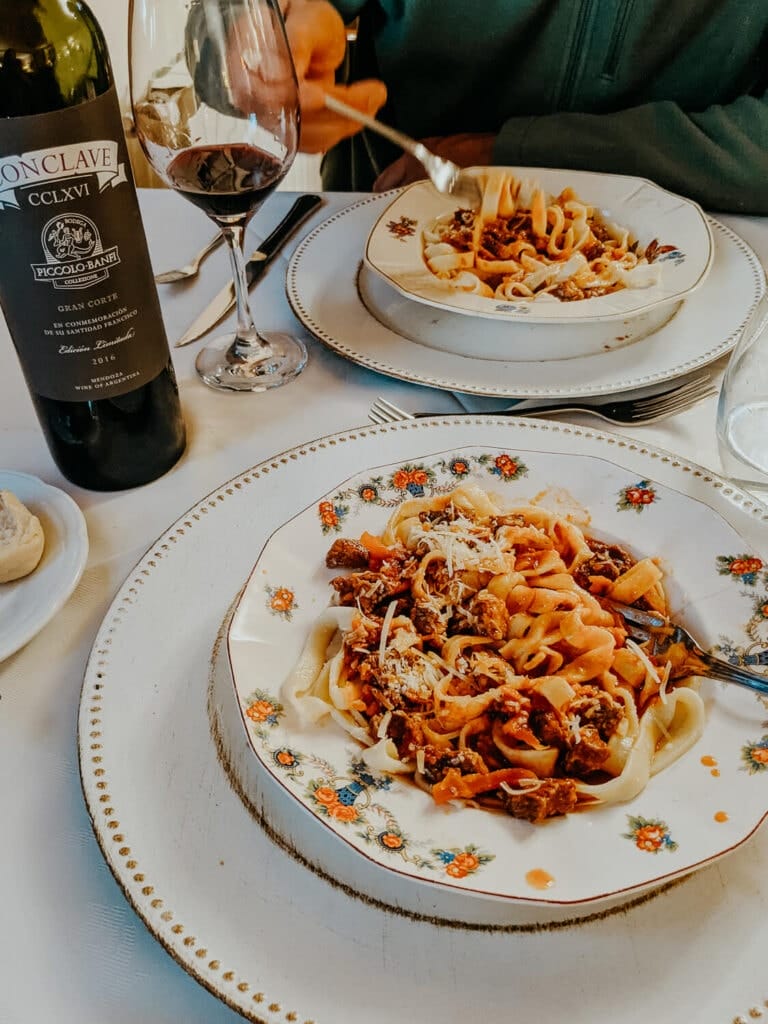 Two bowls of spaghetti in antique bowls and a bottle of wine