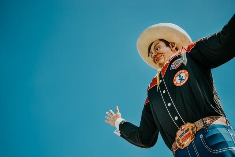 Big Tex, a large statue of a cowboy, stands up in the blue sky