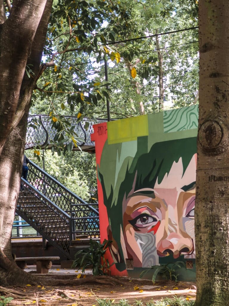 A staircase and bridge cover train tracks behind a mural of a womans face