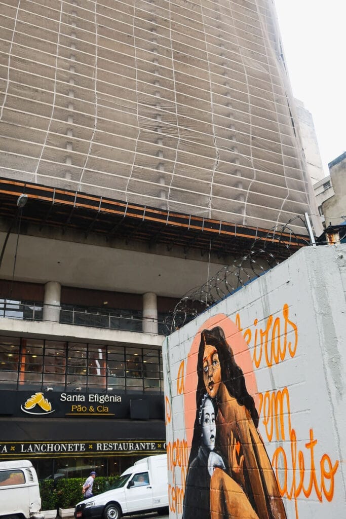 Graffiti on a brick wall in front of a modern skyscraper