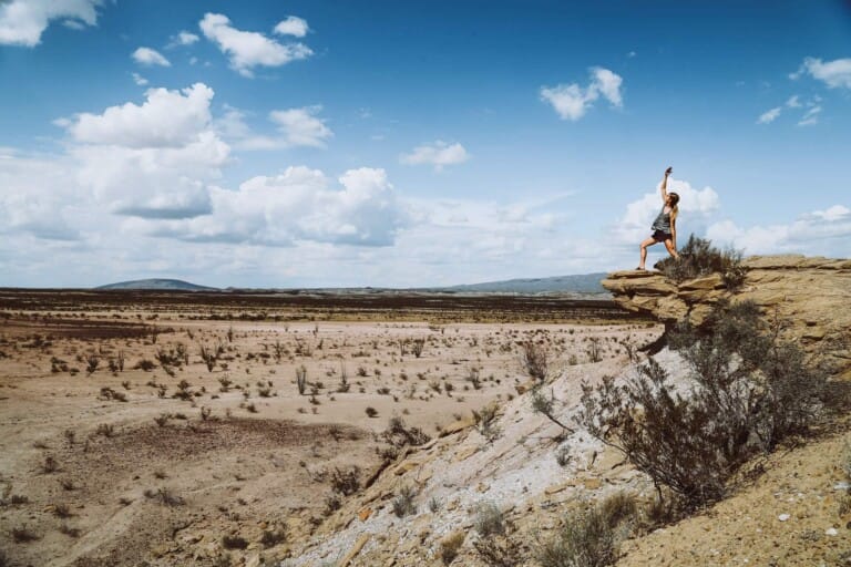 A woman does warrior pose in the desert