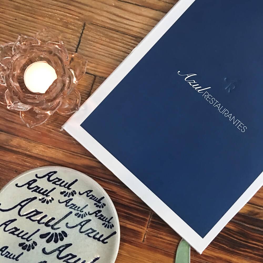 A blue restaurant menu and a candle on a table