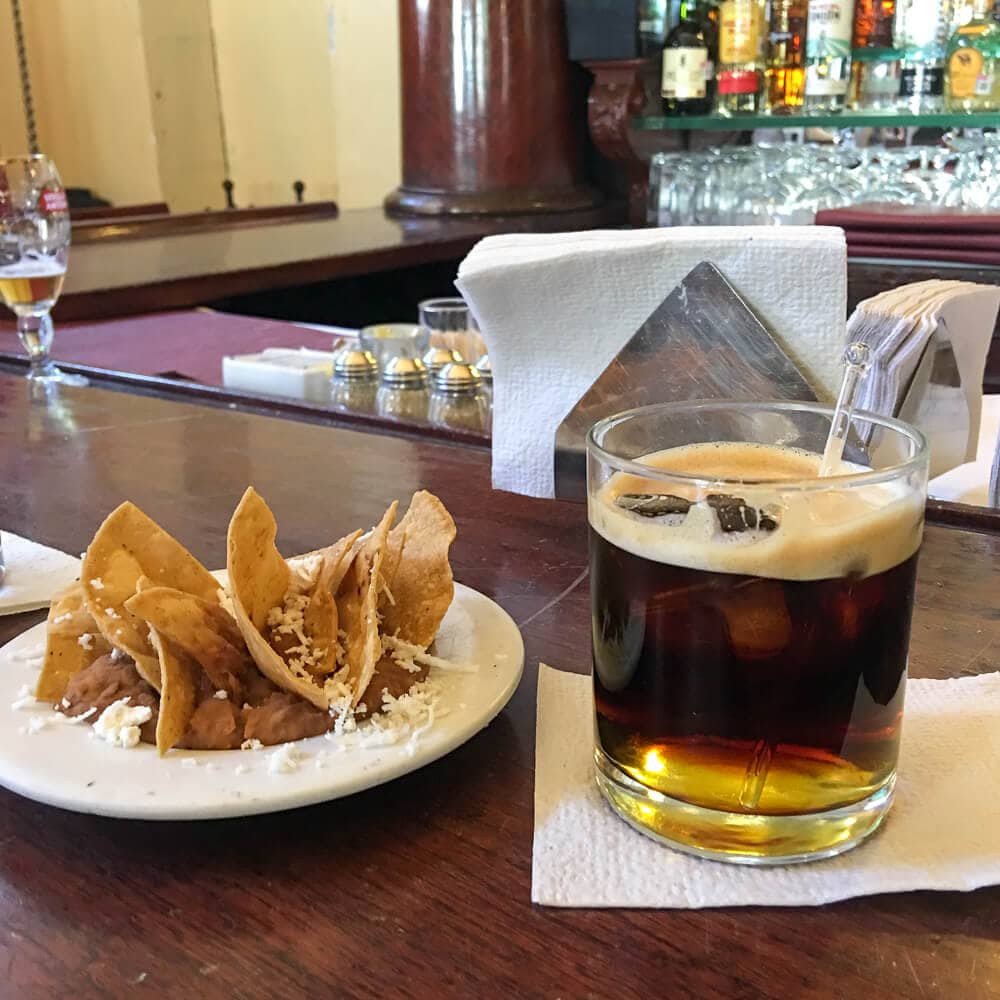 A plate of chips and a cocktail on a bar