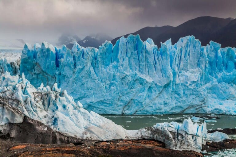 A bright blue glacier on a cloudy day