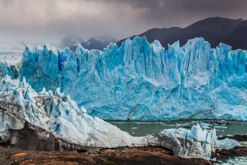 A bright blue glacier on a cloudy day