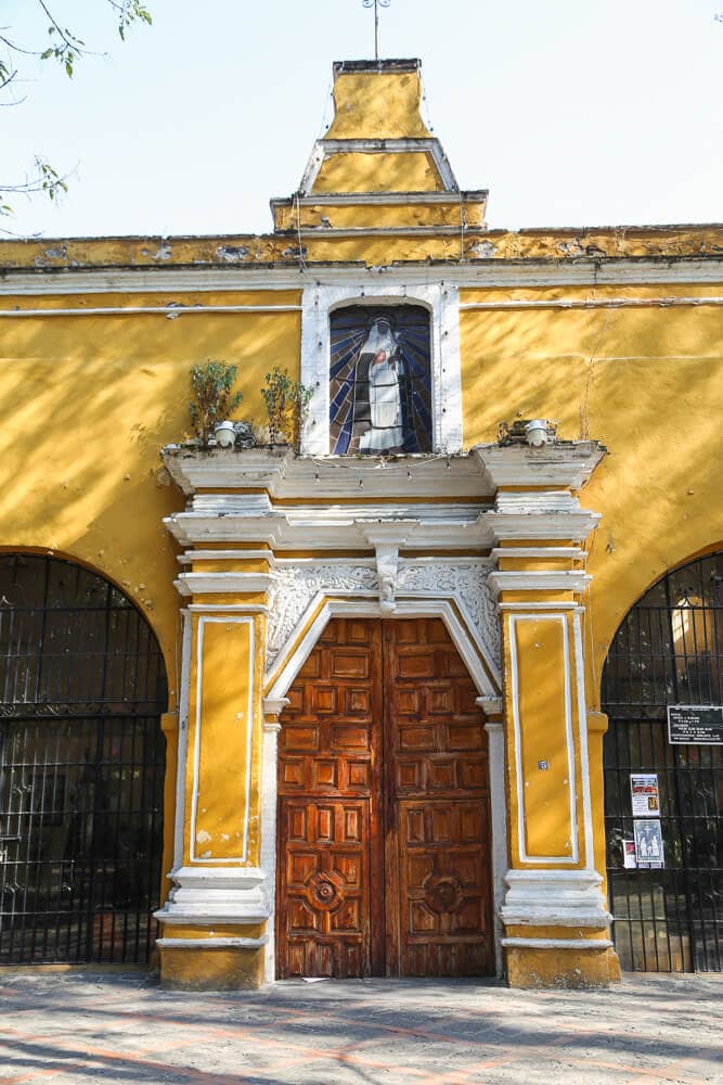A yellow church with a wooden carved door