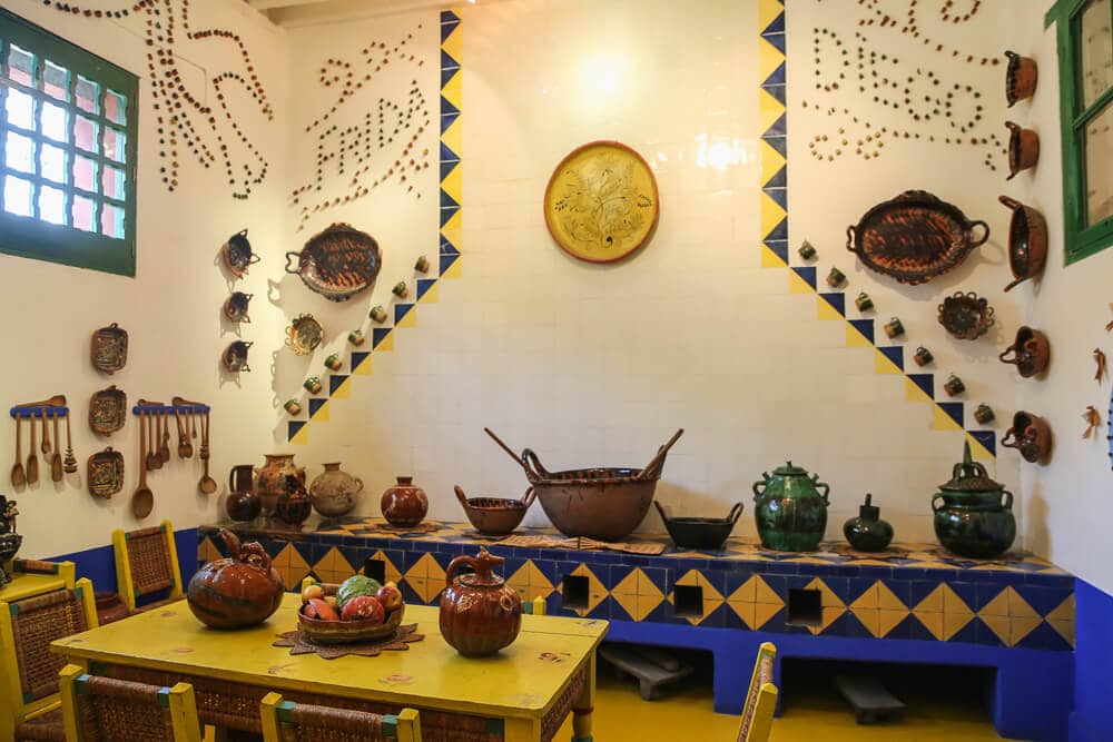 A yellow table in a kitchen with pots and jugs on a tile table