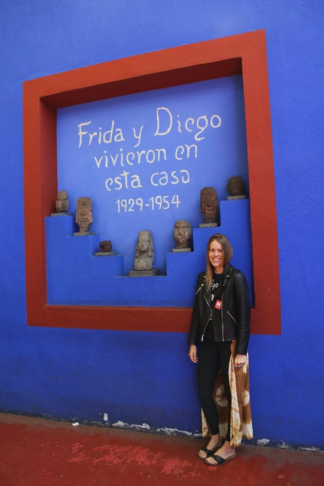 A woman stands in front of a blue wall