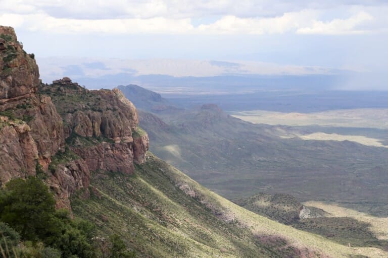 A cliff drops down to the desert below