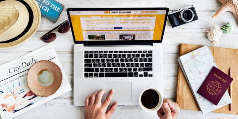 A lay flat photo shot from above of a person using a laptop and holding a cup of coffee