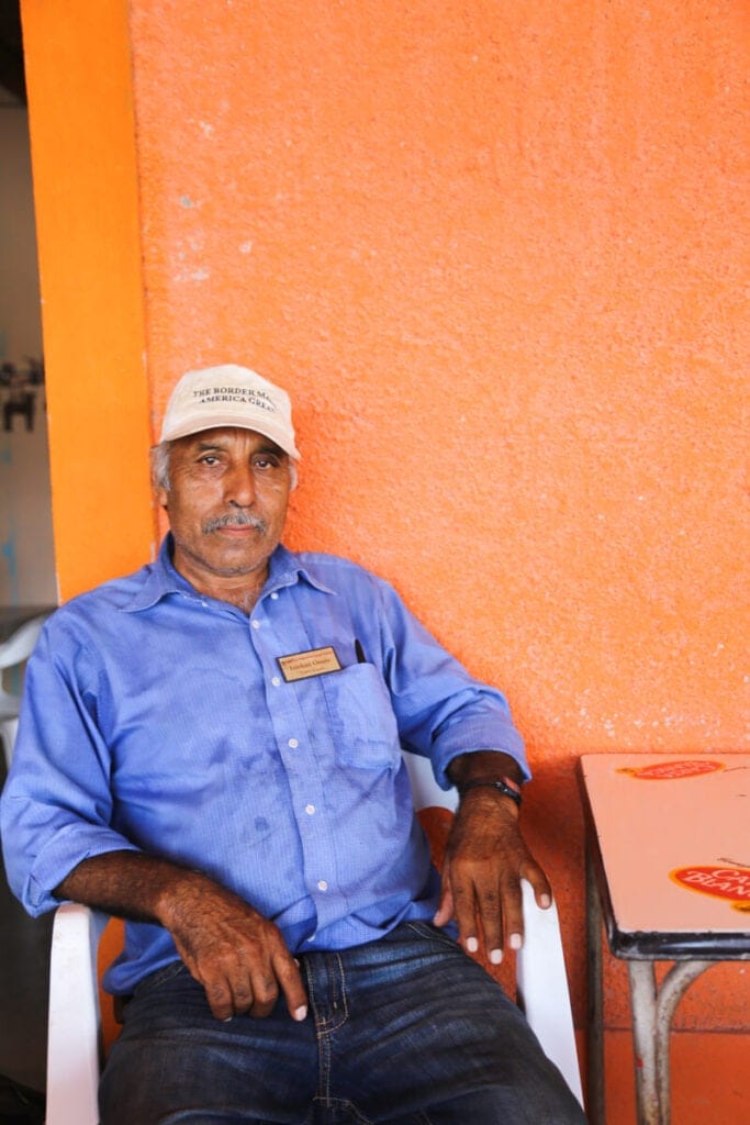 A man sits in front of an orange wall