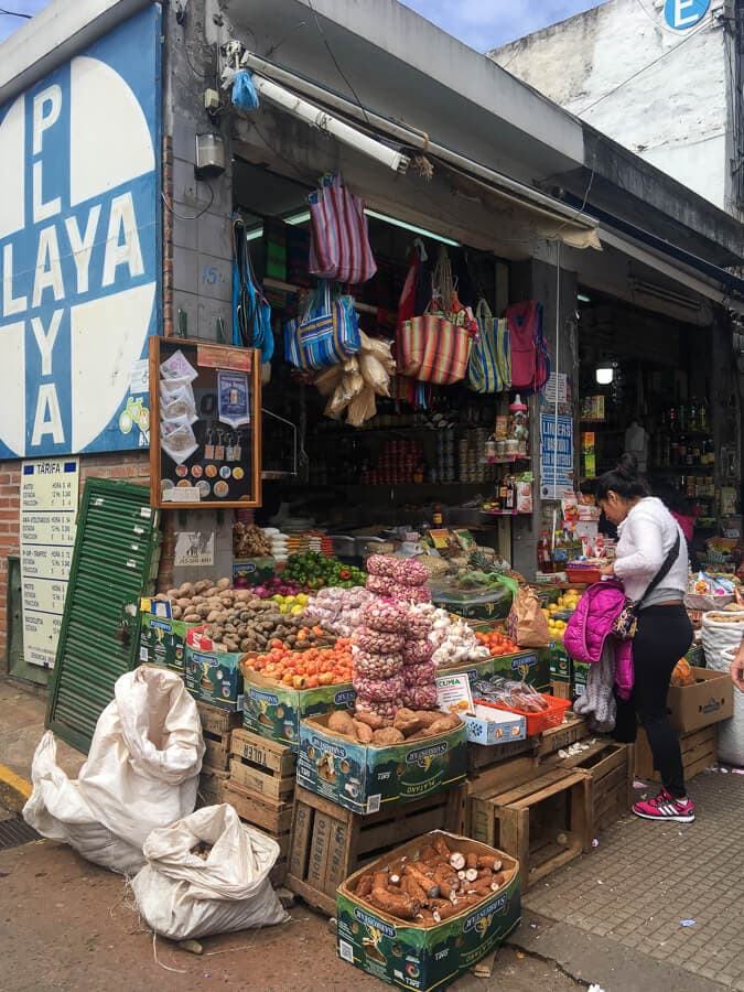 A vegetable stand with boxes of fruit and grains on the sidewalk