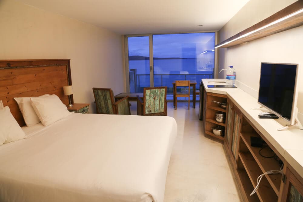 A king bed with white bedding in a hotel room by the ocean