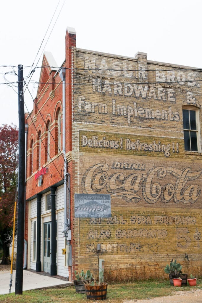A two story brick building with garage doors and a coca-cola mural on the side