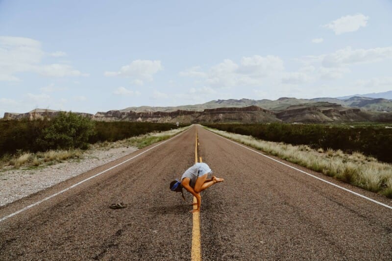 A woman does a yoga pose in the middle of the highway