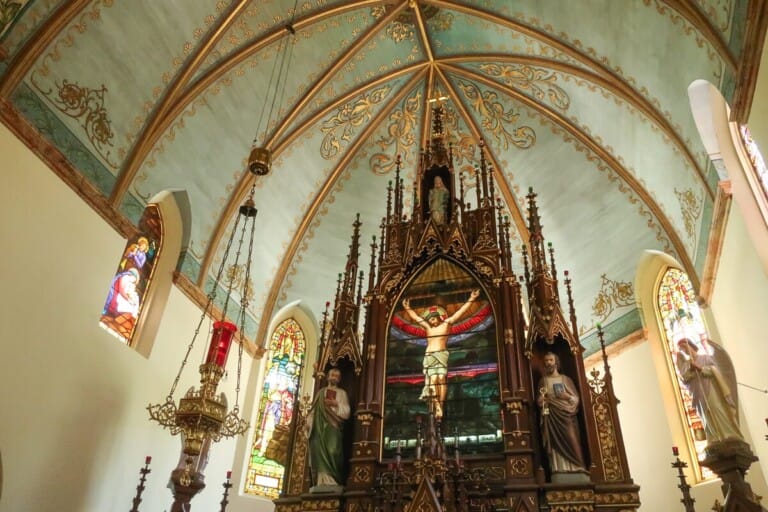 A statue of Jesus hangs from a wooden alter in a church