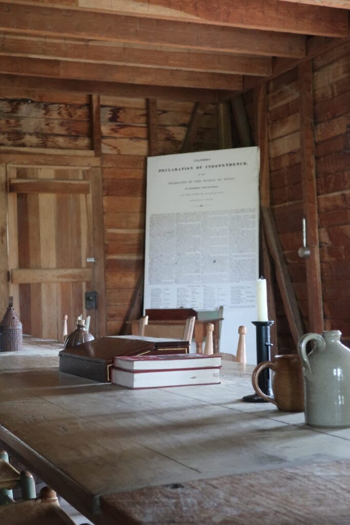 A table with antiques with a recreation of the Texas Declation of Independence in the background