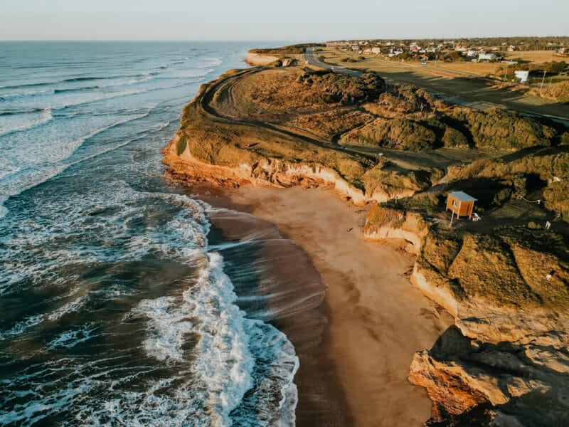Drone photo of waves washing against a cliffside beach in Chapadmalal Argentina