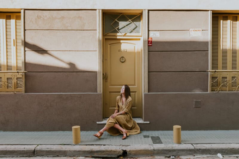 A woman in a yellow dress sits on a door stoop in Palermo Soho Buenos Aires