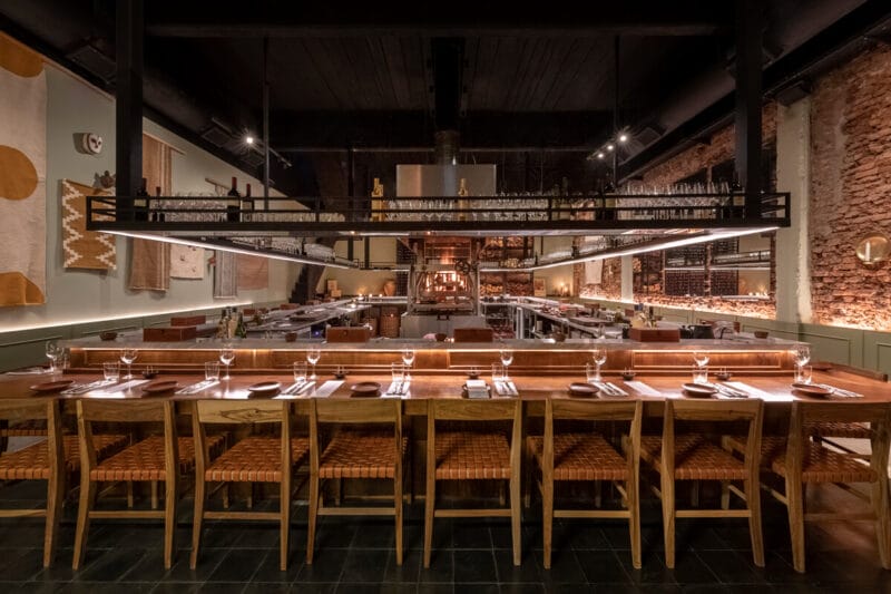 The dining room at the best dining experience in Buenos Aires with a grill in the center of the room and bar seating circling the grill