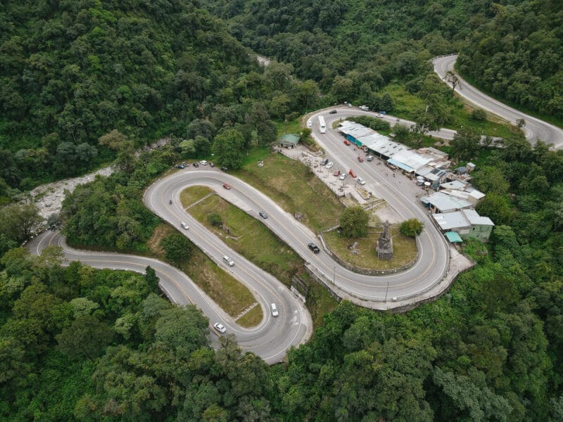 An aerial shot of a weaving road in a lush green jungle