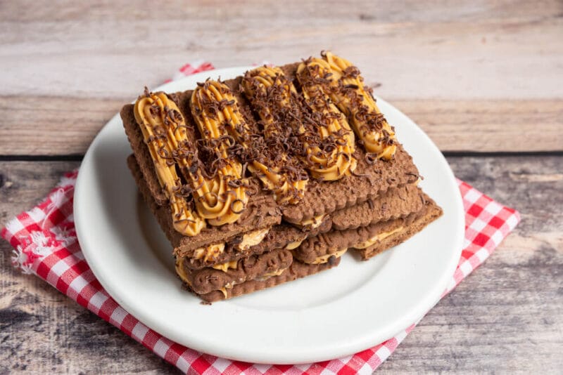 A chocotorta presented on a white plate placed on a white and red checkered napkin