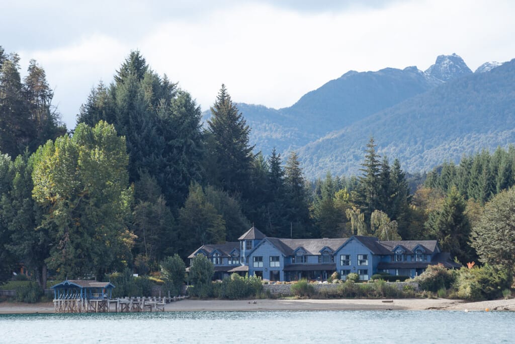 A blue cabin of a luxury Patagonia lodge sits by the lake shore