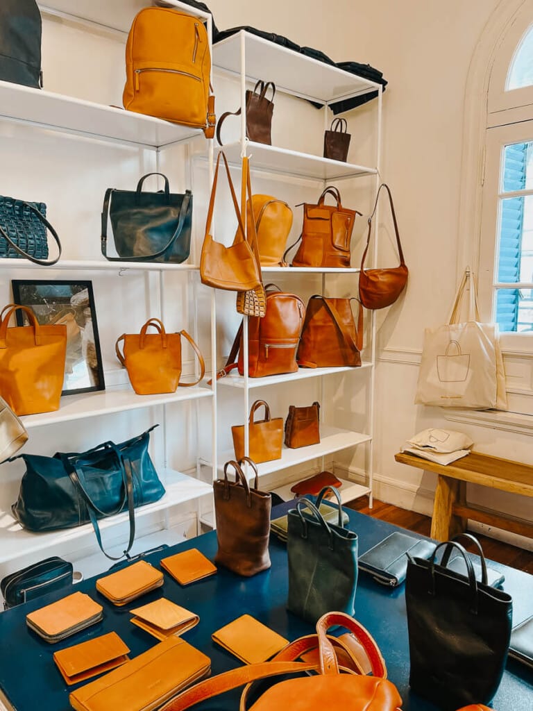 Leather bags stand on white shelves in a Buenos Aires leather shop