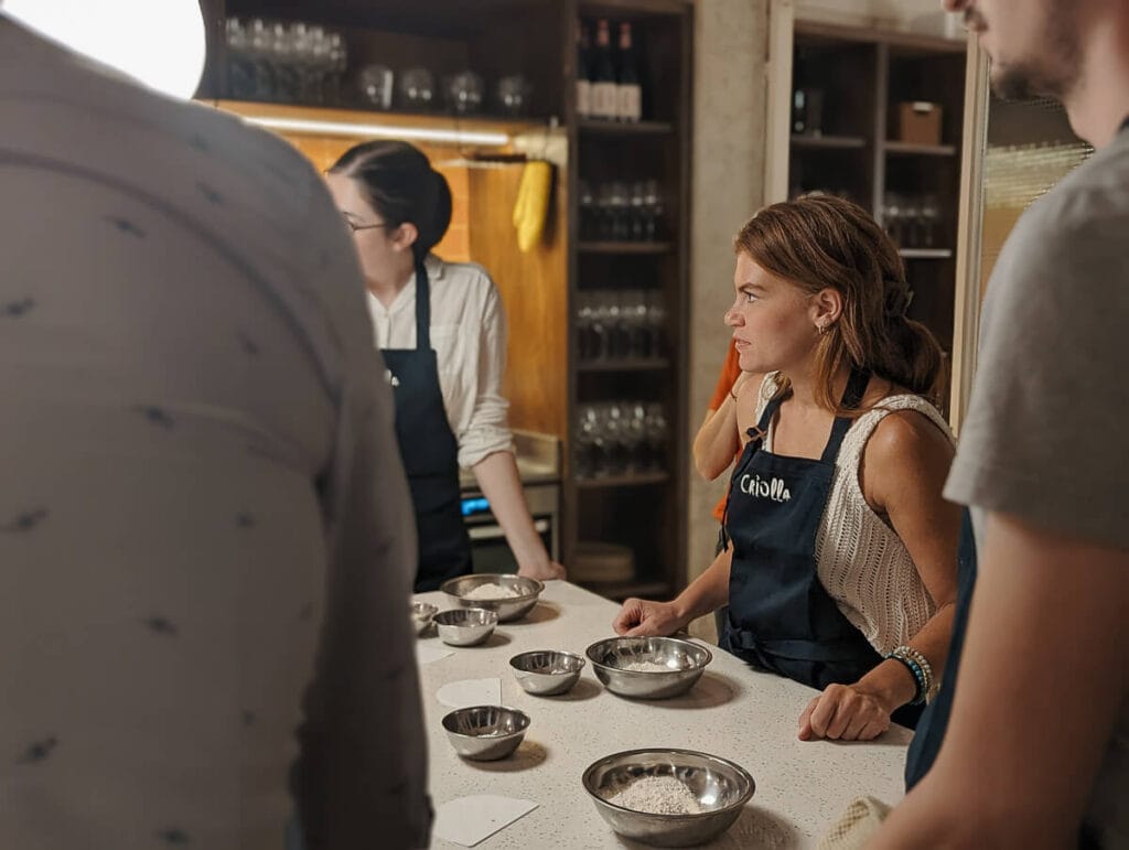 A woman stands at a table at a Buenos Aires cooking class attentive to the chef's instructions