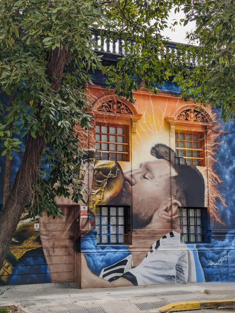 A mural of Messi kissing the world cup trophy on a historic building in Argentina