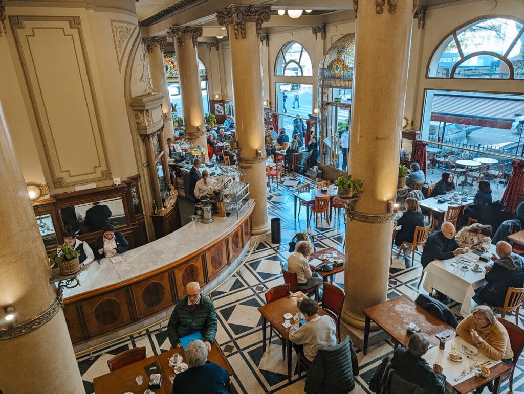 A historic European style cafe in Almagro Buenos Aires with diners sitting at wooden tables and a bar to the left