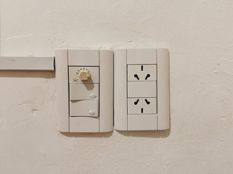 An Argentina outlet on a white wall next to light switches