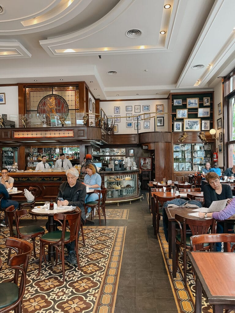 Dinners sip on coffee at small marbled tables in a historic Buenos Aires cafe