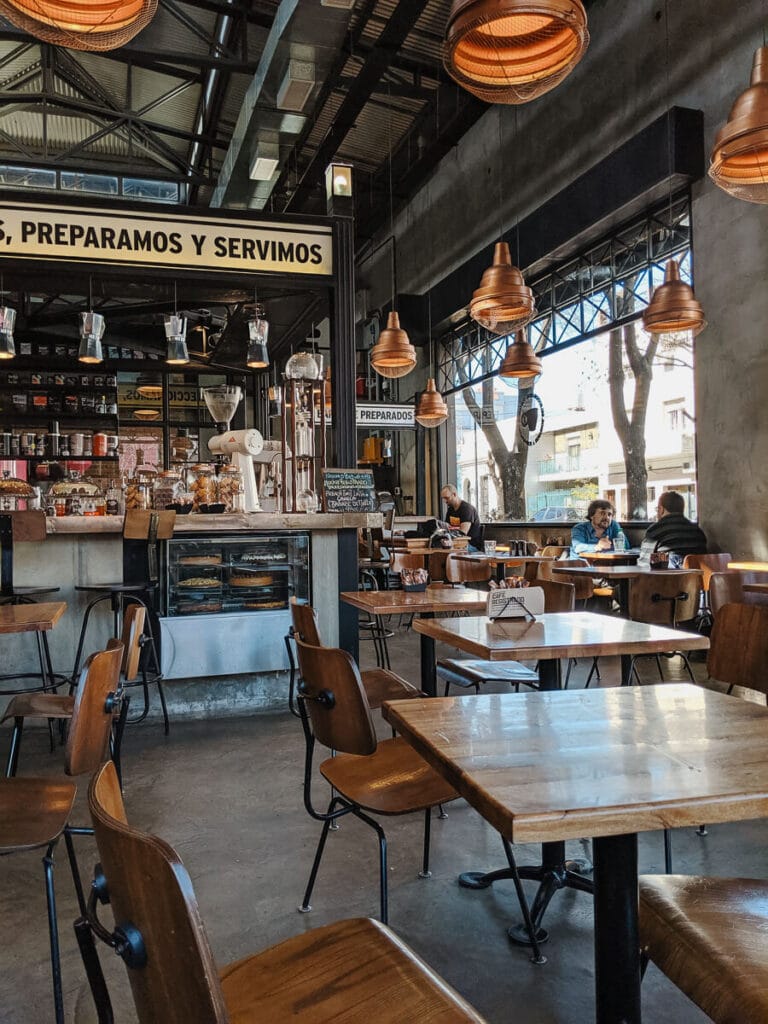 Wooden tables and chairs in a huge concrete space in a Buenos Aires cafe