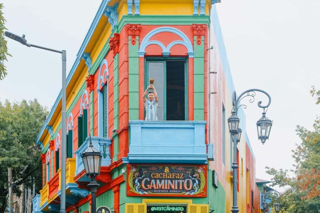 A statue of Messi holds the World Cup trophy into the air from the famous balcony of the colorful Caminito corner in La Boca Buenos Aires