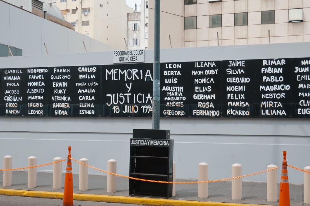 A black and white mural calling for justice lists all the names of the victims of a terrorist attack on a Jewish community center
