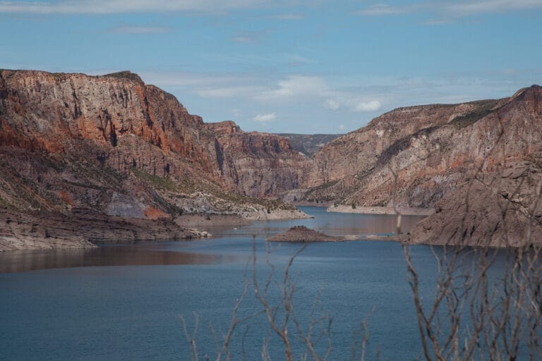 A deep blue lake under red and orange mountains in San Rafael Argentina